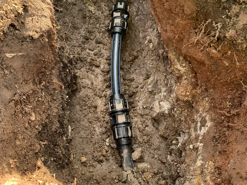 After — water spraying from a split underground water line, then the same line repaired with new fittings