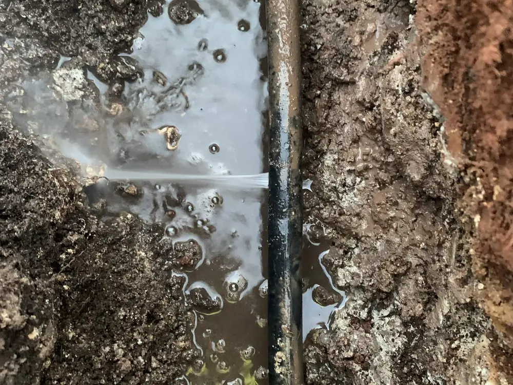 Before — water spraying from a split underground water line, then the same line repaired with new fittings