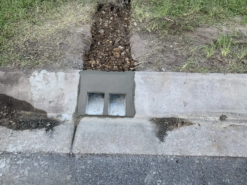 twin kerb adaptors finished in concrete where new stormwater lines discharge to the street